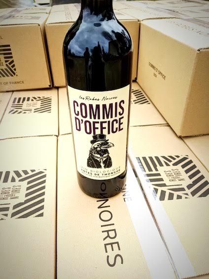 Bouteille de la cuvée Commis d’office, syrah en monocépage du domaine Les Robes Noires, posée sur des cartons du domaine.