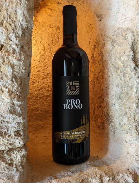 Bouteille de la cuvée Pro Bono, vin rouge du domaine Les Robes Noires, dans une niche de pierre.